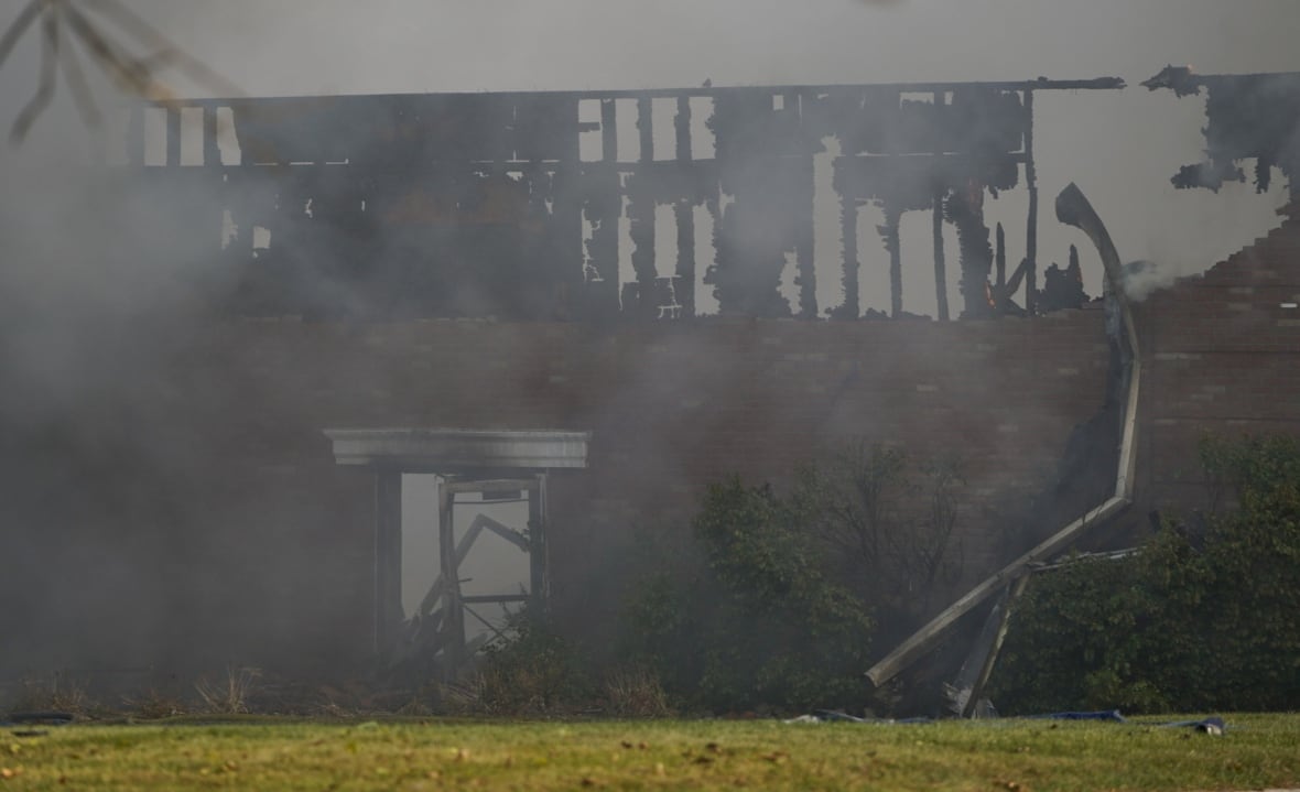 Smokes surrounds a building destroyed by a fire.
