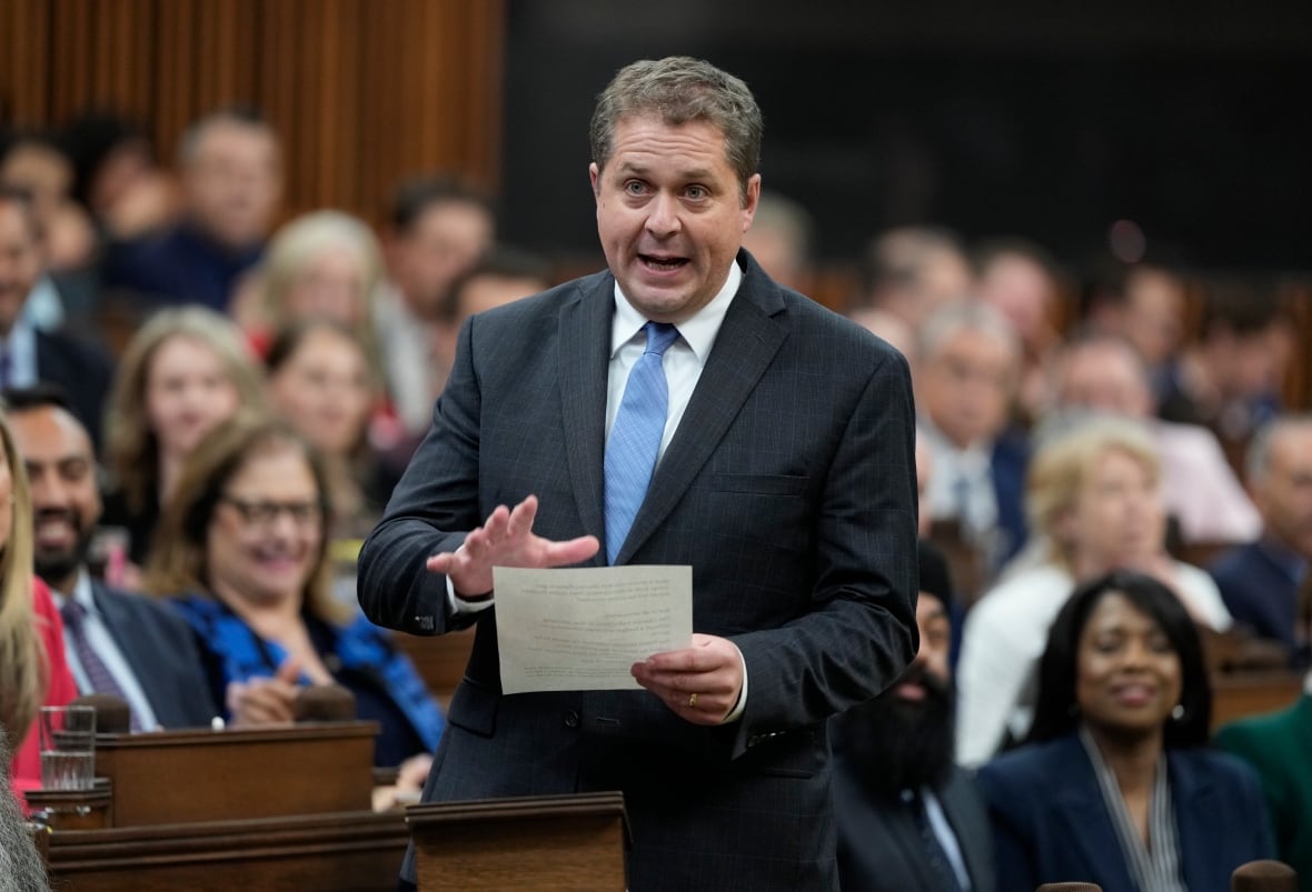 A man wearing a suit reads from a sheet of paper in the House of Commons.