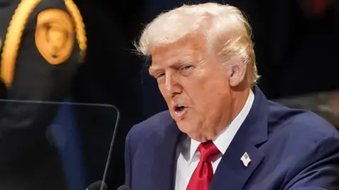 Reuters US president Donald Trump addresses the 80th United Nations General Assembly in New York City on 23 September 2025. He wears a blue suit and a rd tie.