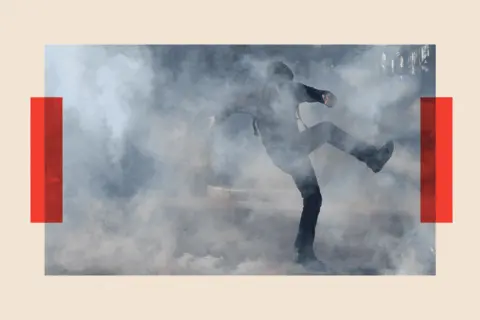 REUTERS/Tom Nicholson A protester runs amid tear gas during clashes with French police