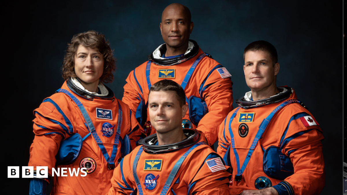 Four Artemis II astronauts in their bright orange flight suits.