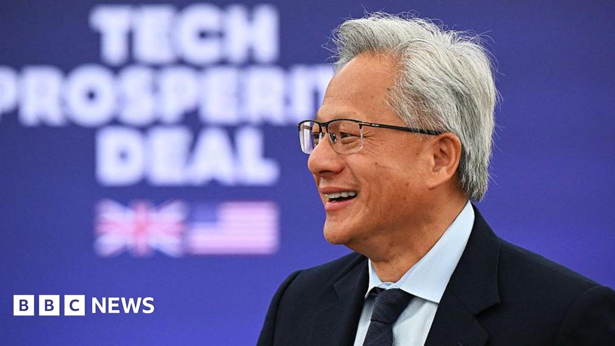 Nvidia CEO Jensen Huang at a Business event hosted by US President Donald Trump and Britain's Prime Minister Keir Starmer. He is smiling and wearing a suit with a tie. He has grey hair and wears glasses.