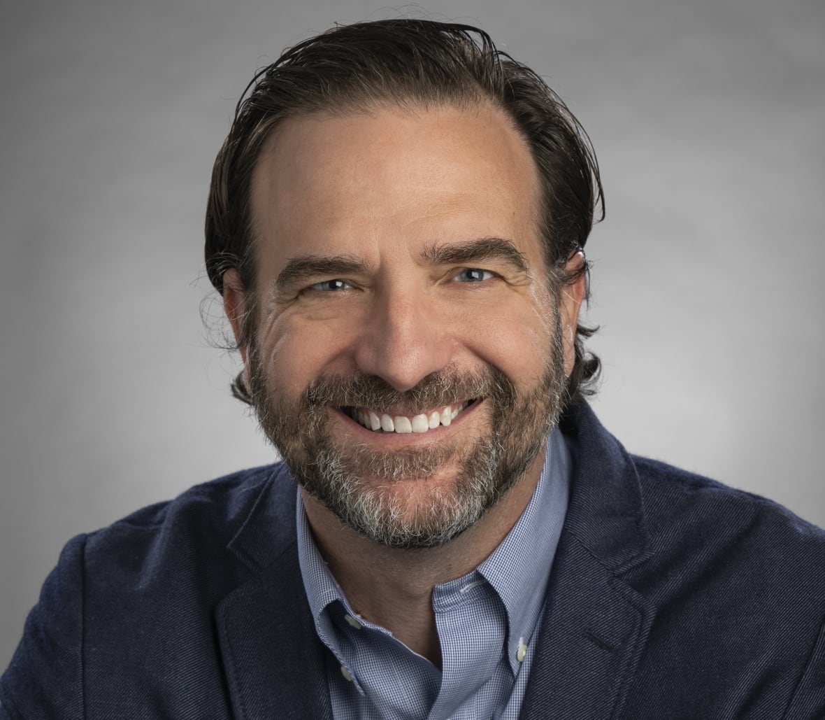 Doctor, caucasian man, is seated and smiling.