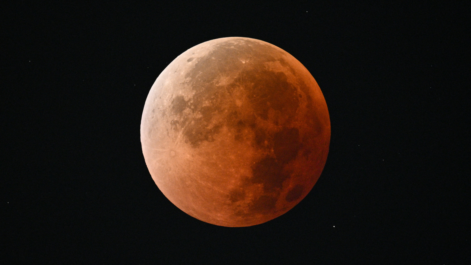 A red full moon is shown against a black sky.