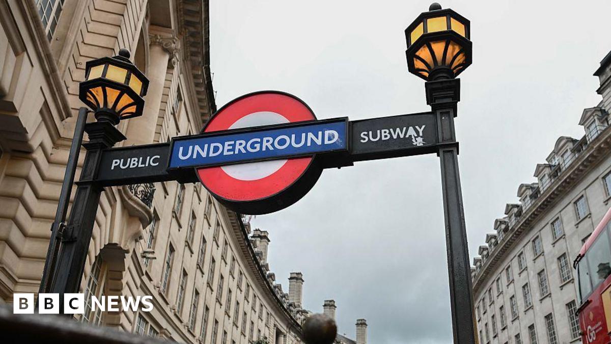 The entrance to a London Underground subway, with the red, whit ea blue Underground logo and yellow lamps.