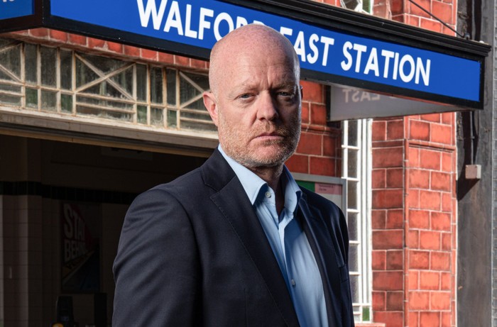 Jake Wood as Max Branning stood in front of Walford East tube station, staring menacingly ahead. He is wearing a light blue shirt paired with a dark coloured suit.
