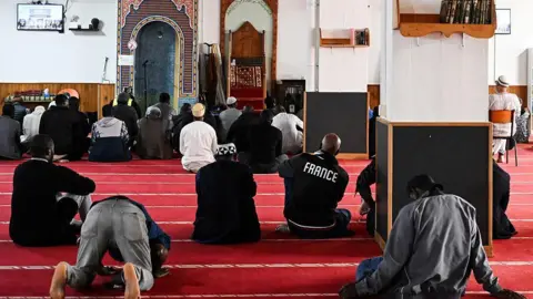 Getty Images Men sit down to pray at a mosque in Paris