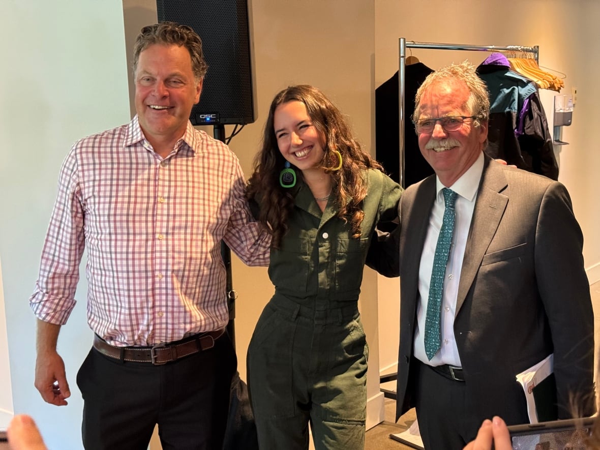 A smiling woman is flanked by two men.