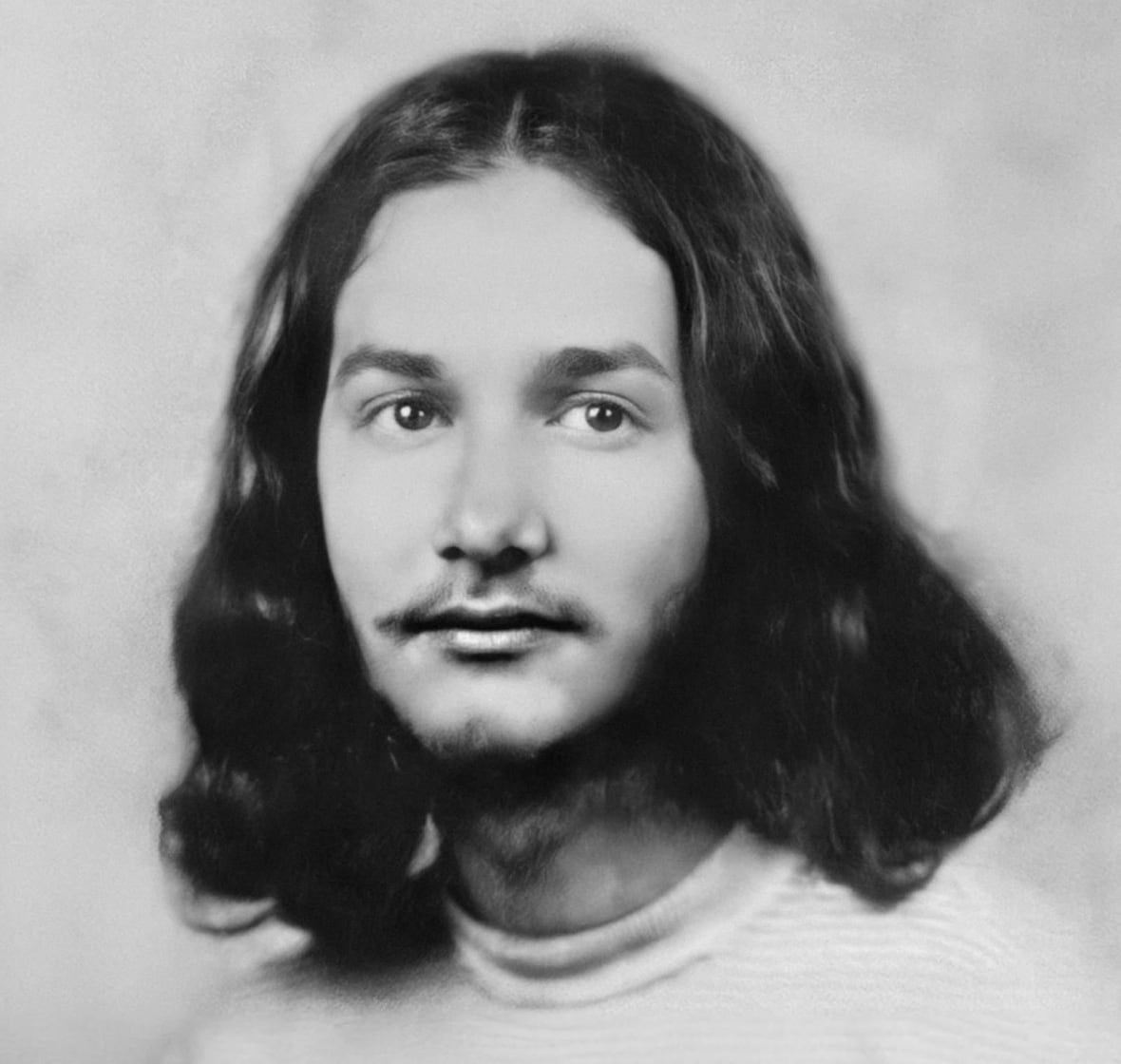A black and white picture from the 1970s of a young man with long hair.