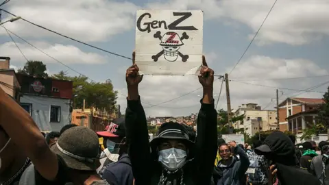 Getty Images A protester with their face covered by a mask holds up a poster that says 'Gen Z'