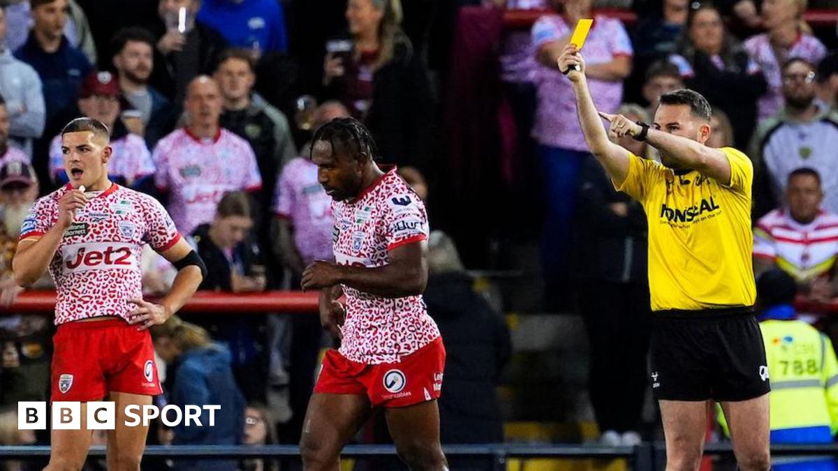 Edwin Ipape being shown a yellow card by referee Liam Moore