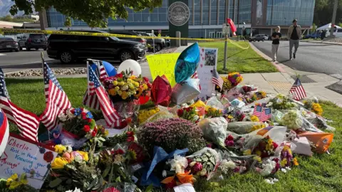 BBC / Christal Hayes A memorial is on display with flowers and signs commemorating Charlie Kirk at the campus. 