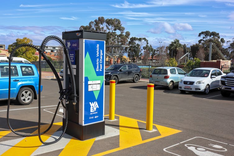 an EV charger in a car park with cars parked nearby.