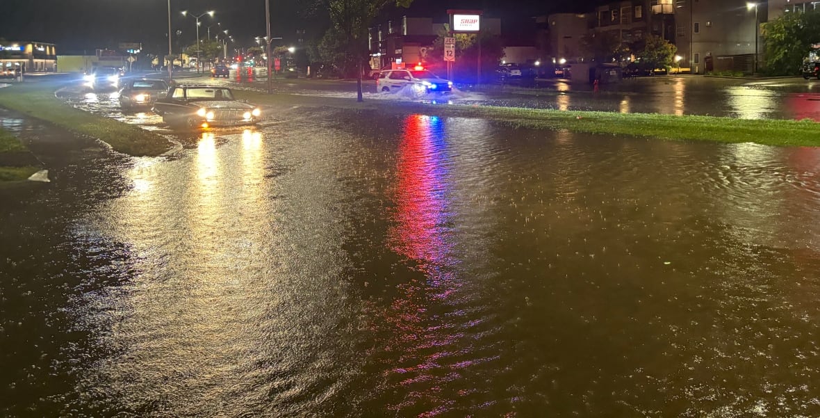 Cars drive into a flooded street after a heavy rain