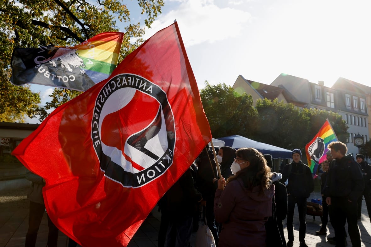 People gather and wave red Antifa flags during an outdoor vigil.
