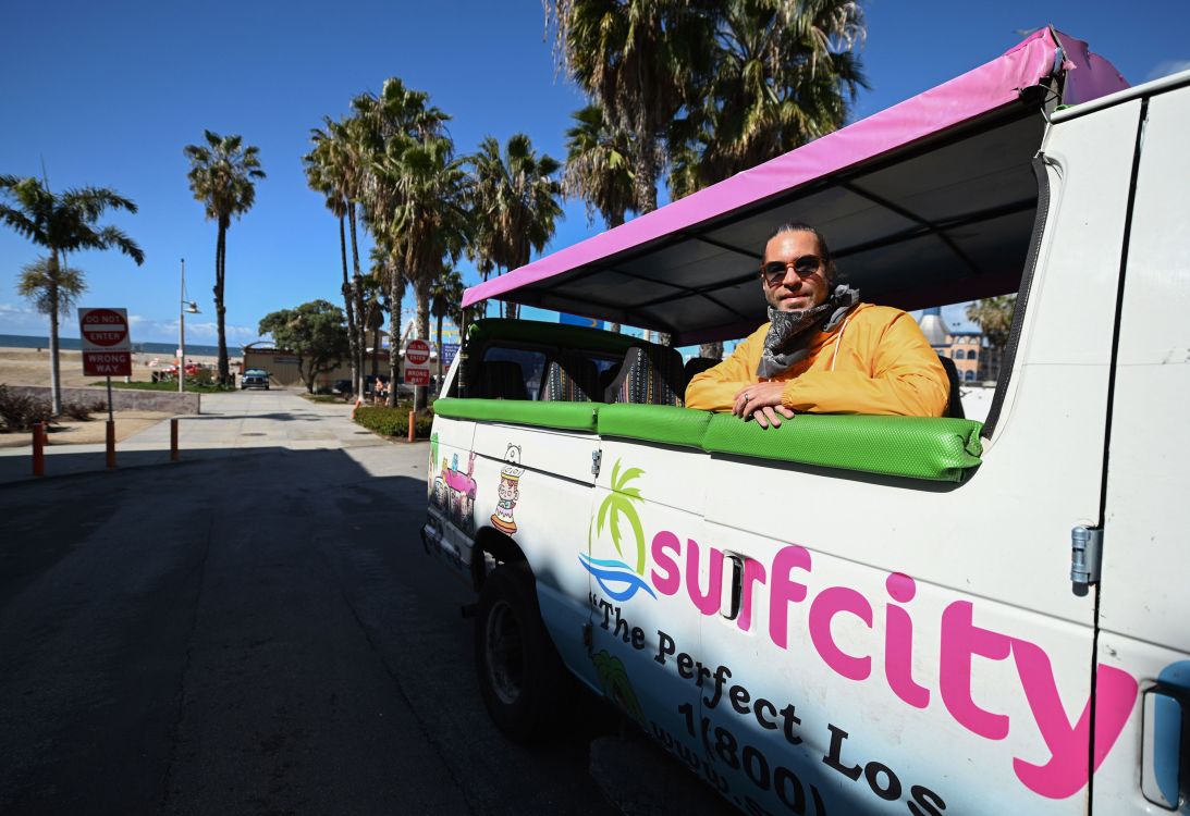 Adam Duford, owner of Surf City Tours, poses in one of his tour vans in Santa Monica, California, on March 23, 2020. This year's tourism drop has affected his business.