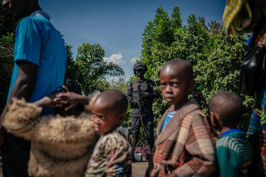 A Rwandan border officer stands guard as displaced people wait at the border between the Democratic Republic of Congo and Rwanda on May 19, 2025.