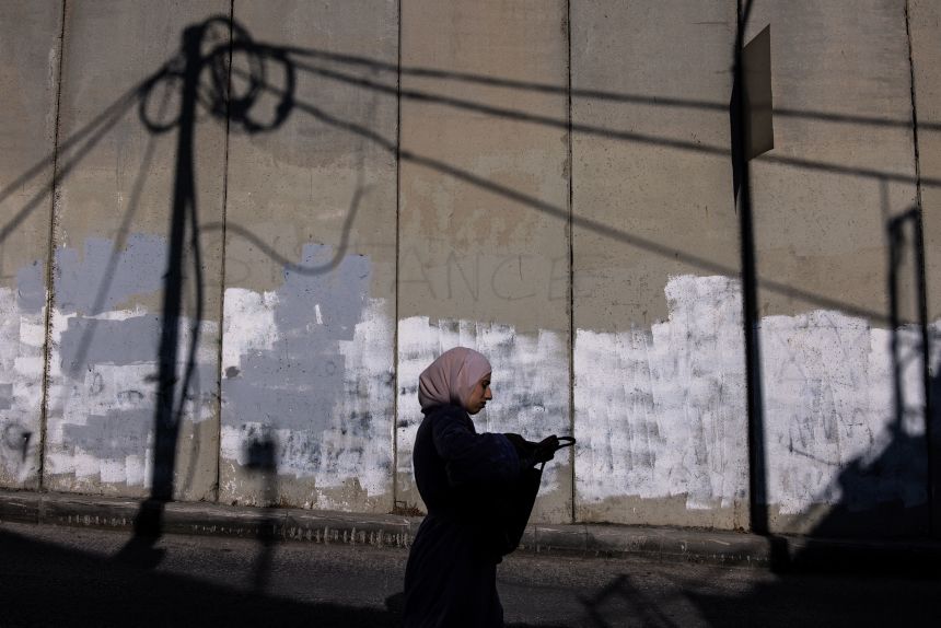 A Palestinian woman walks along the separation wall outside the Palestinian town of Abu Dis.