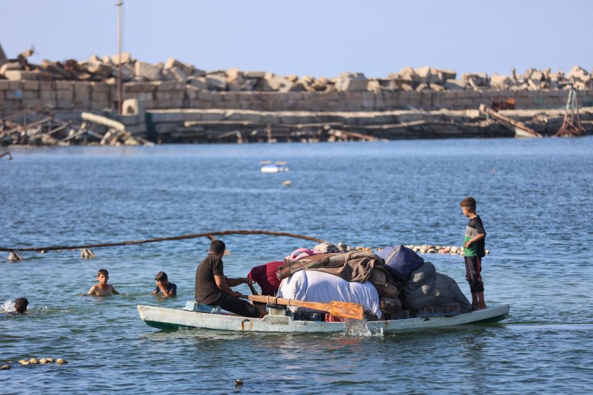 Displaced Palestinians transport their belongings on their fishing board as they flee Israeli bombardment southward, by sea from the Gaza City port on Thursday, September 18.