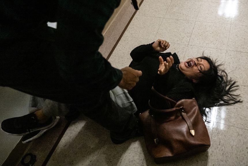 A federal agent pushes a woman to the ground in a confrontation at an immigration courthouse Thursday in New York City.