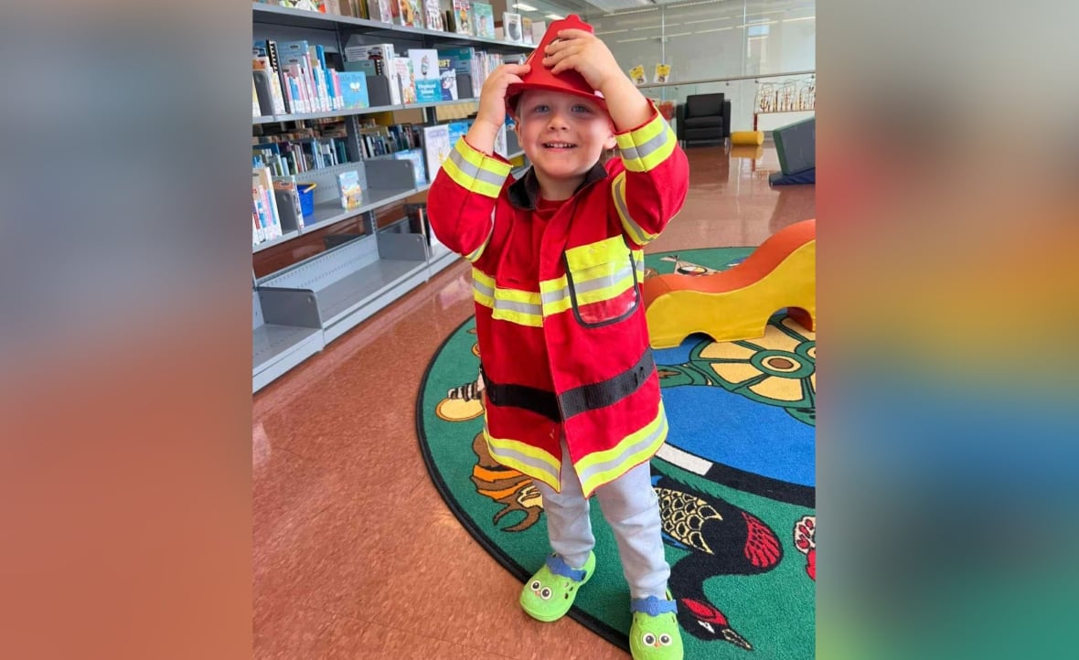 young boy dressed up as fireman standing in the library