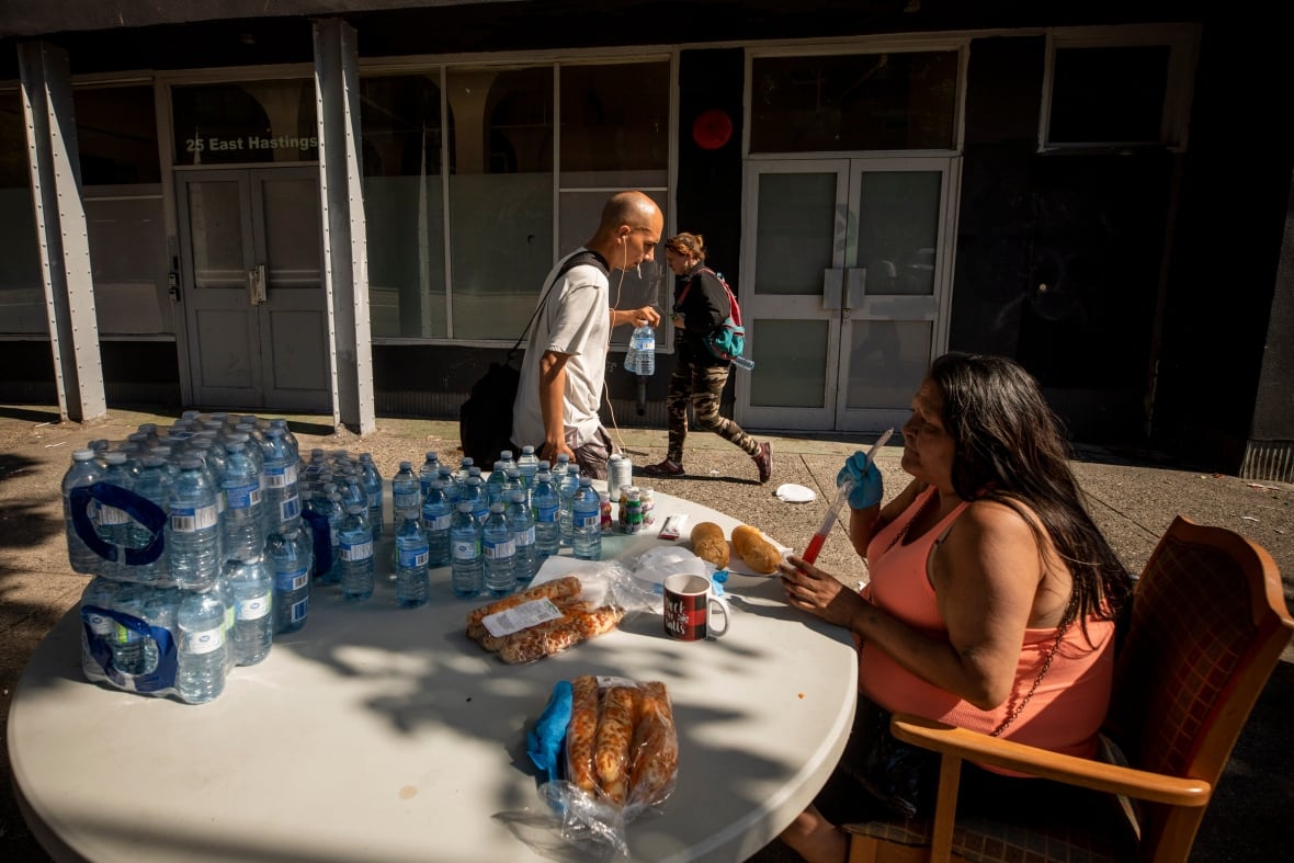 A woman who goes by the name ChillyBean hands out bottled water to residents in the Downtown Eastside neighbourhood in Vancouver on June 28, 2021.