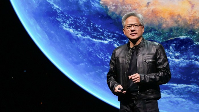 Jensen Huang stands on stage in a black leather jacket, with a large image of Earth displayed behind him.