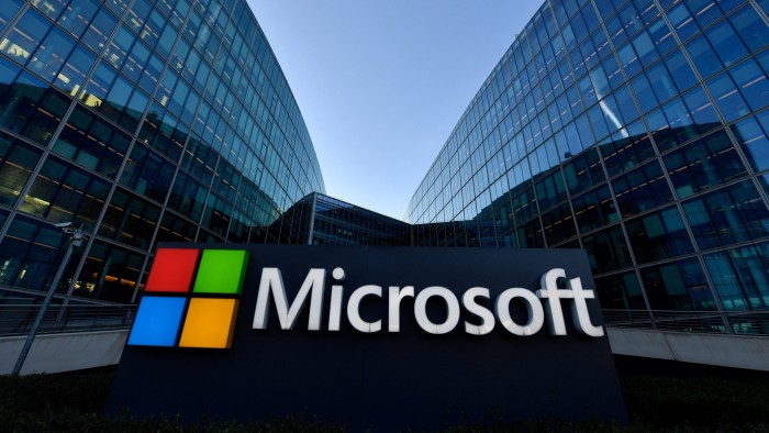 The Microsoft logo is displayed in front of the company's French headquarters, with modern glass office buildings in the background.