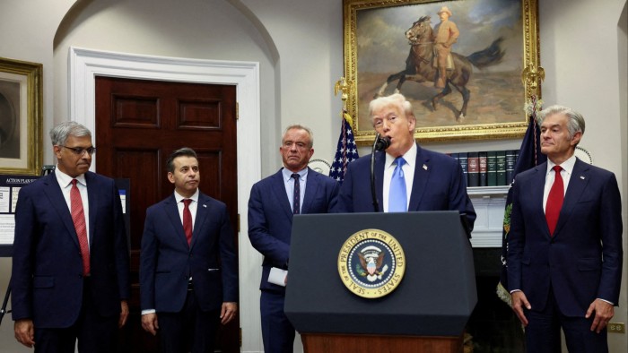 Donald Trump speaks at a podium flanked by Mehmet Oz, Jay Bhattacharya, Marty Makary, and Robert F. Kennedy Jr. in a White House room.