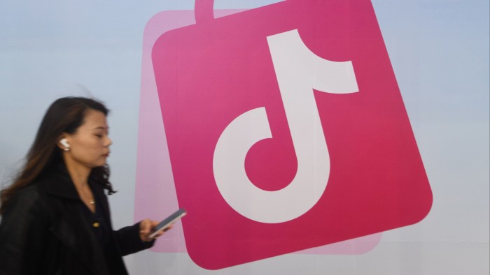 A woman walks past a TikTok logo