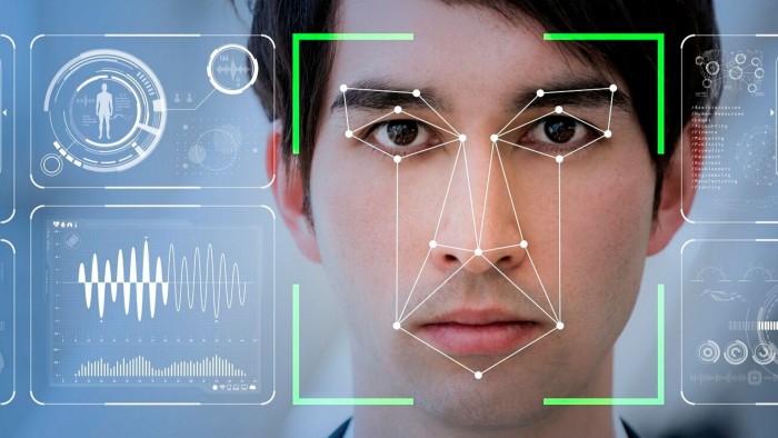 A man’s face overlaid with a digital facial recognition grid, surrounded by futuristic data and biometric interface graphics.