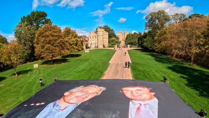 Activists unfurl a large banner showing a photo of Donald Trump posing with Jeffrey Epstein on the Long Walk outside Windsor Castle.