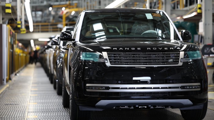 A black Range Rover SUV at the front of a production line inside the Jaguar Land Rover manufacturing plant.