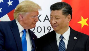 Donald Trump and Xi Jinping facing each other during a meeting, with U.S. and Chinese flags visible in the background.