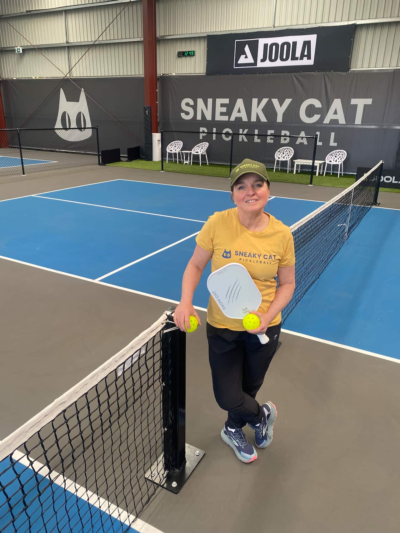 A woman smiling at a pickleball court.