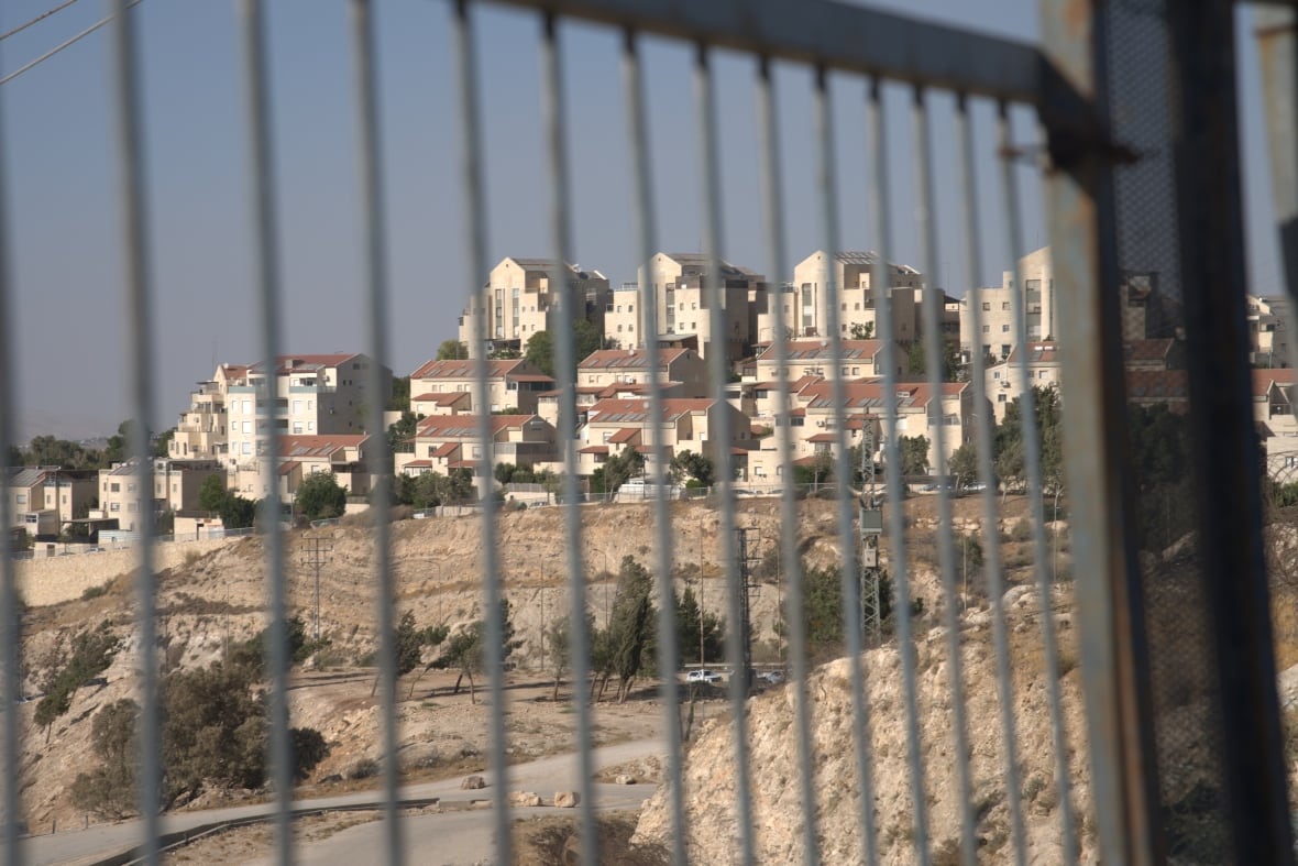 A settlement is seen through an iron gate.
