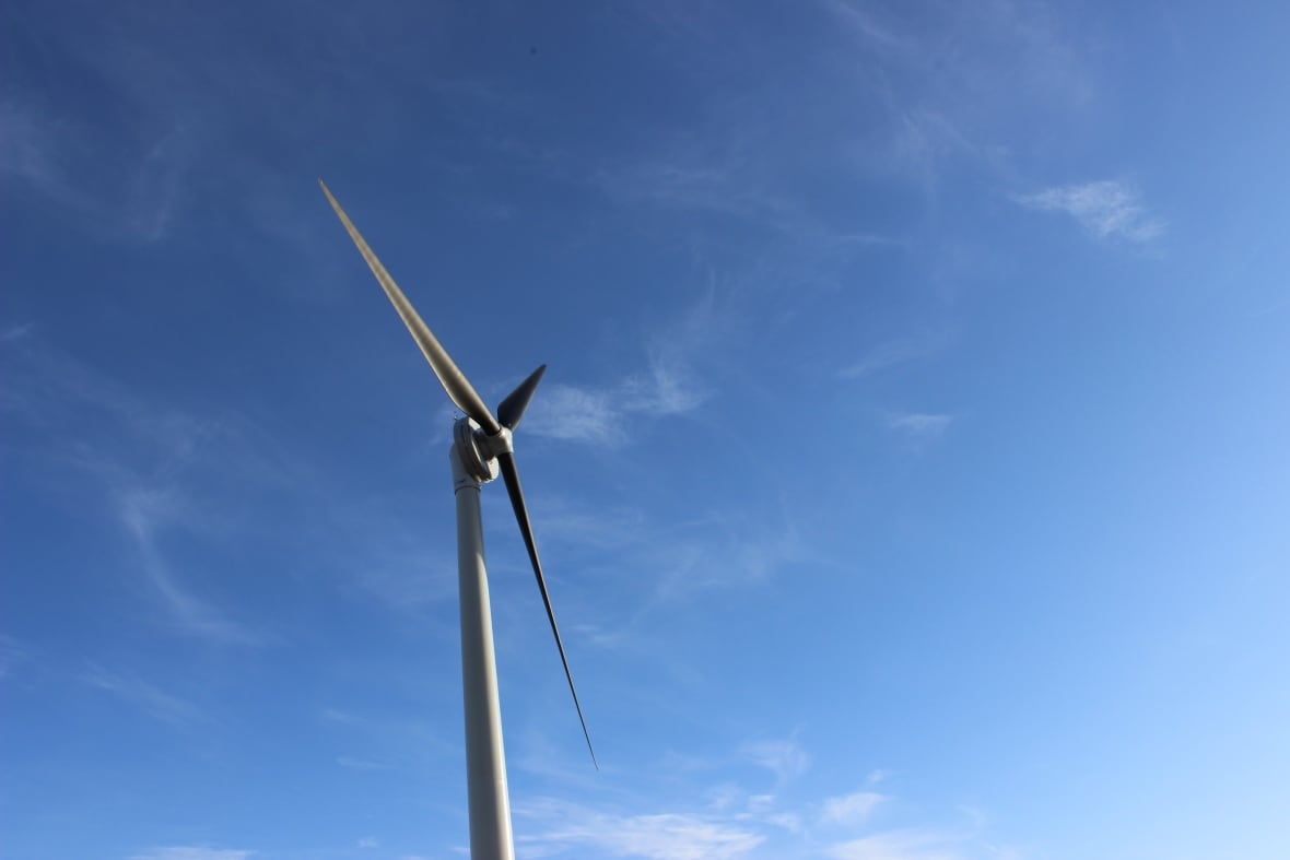 A wind turbine against a mostly blue sky.