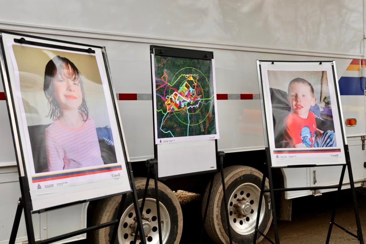 Three easels, one with a large photo of Lilly Sullivan on the left, middle with a large search map, right a large photo of Jack Sullivan. RCMP Van in back.