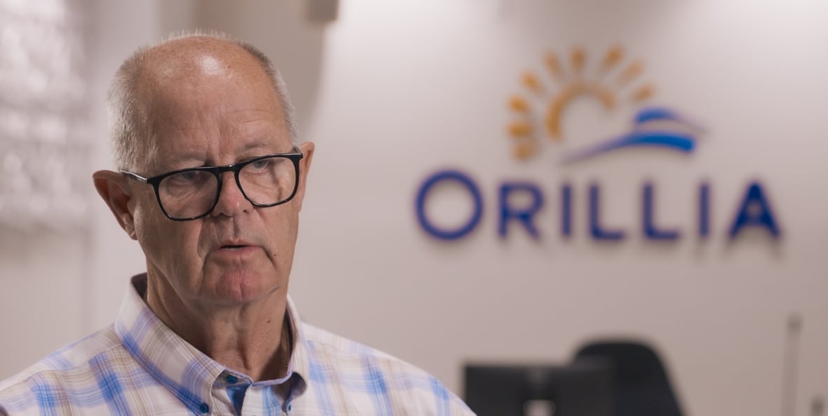 a man with dark glasses and a plaid shirt sits in a boardroom