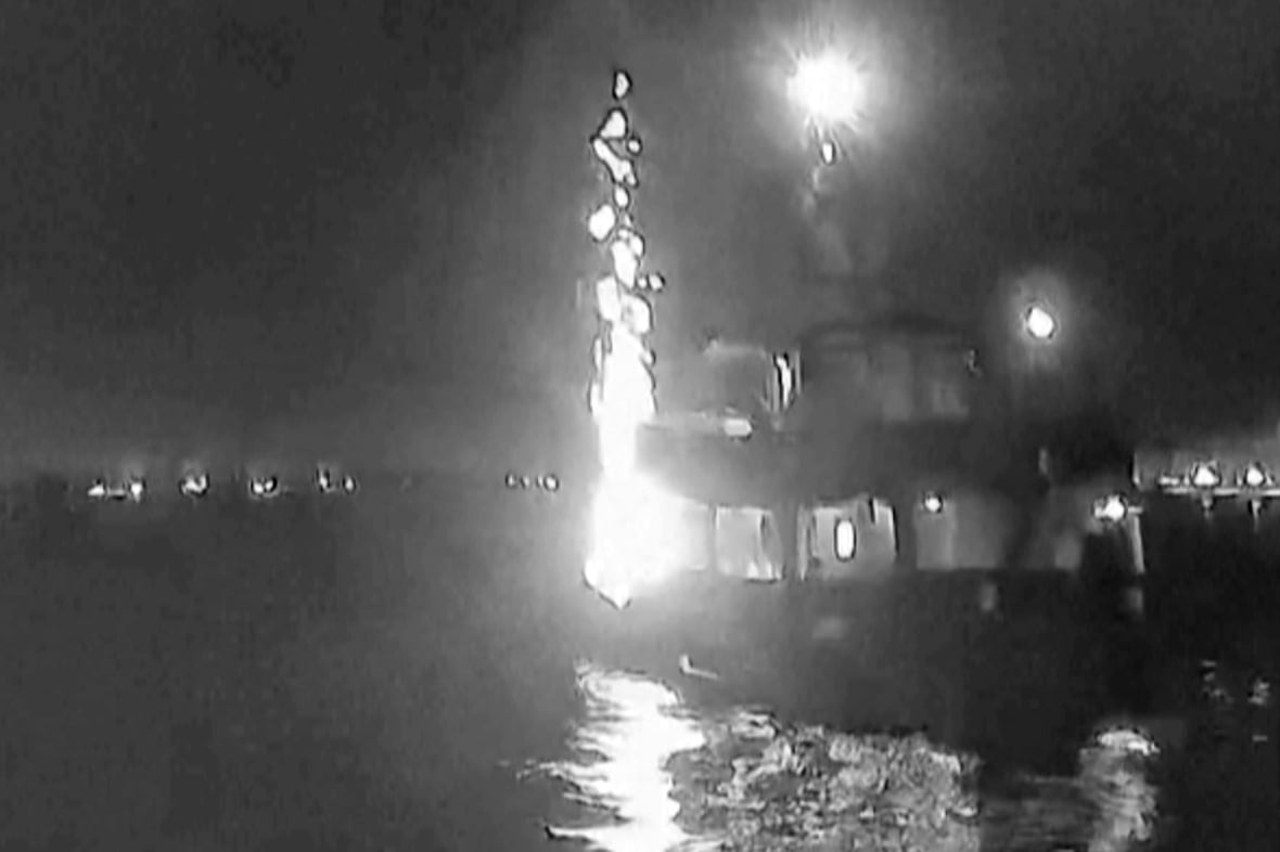 A grainy black and white image of a  boat with flames on it
