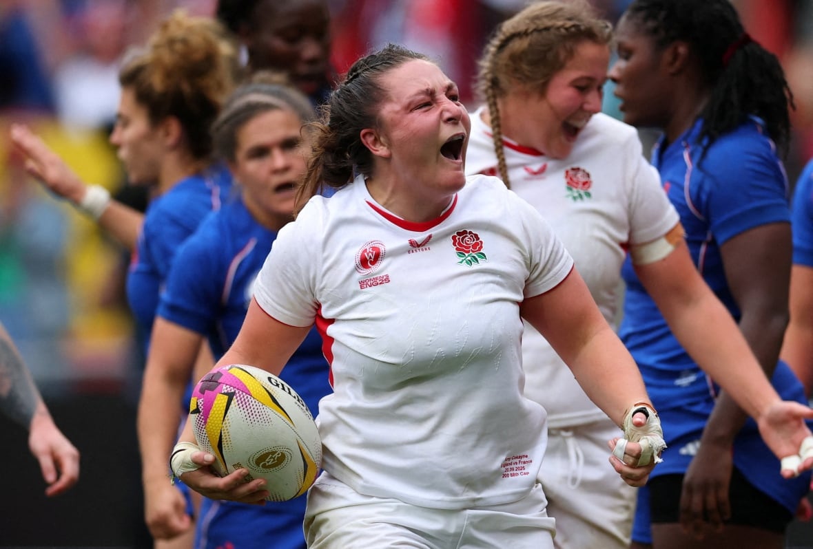 A female rugby player holds the ball  and cheers