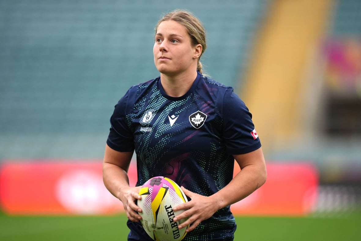 A woman holds a rugby ball