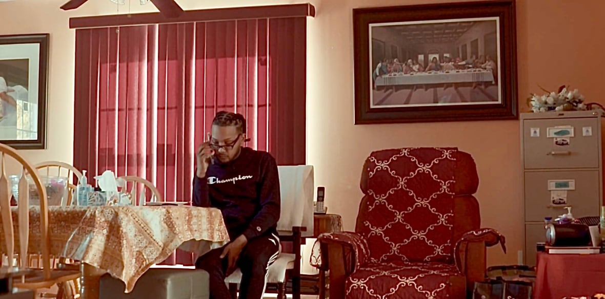 Samuel Provo-Benoit, African Nova Scotian man seated, looking at his phone.