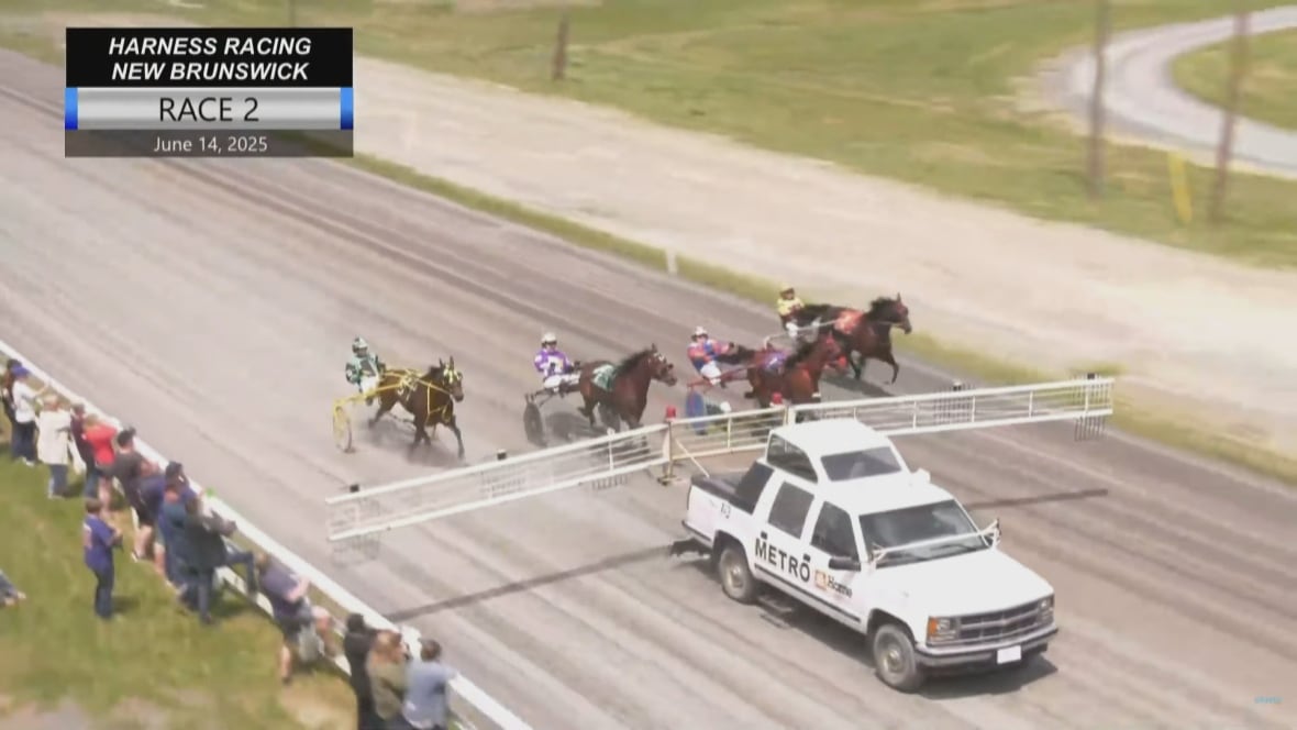 still frame taken from video shows starting truck with gates extended  close to the spectators lined up against the wodoen fence. 