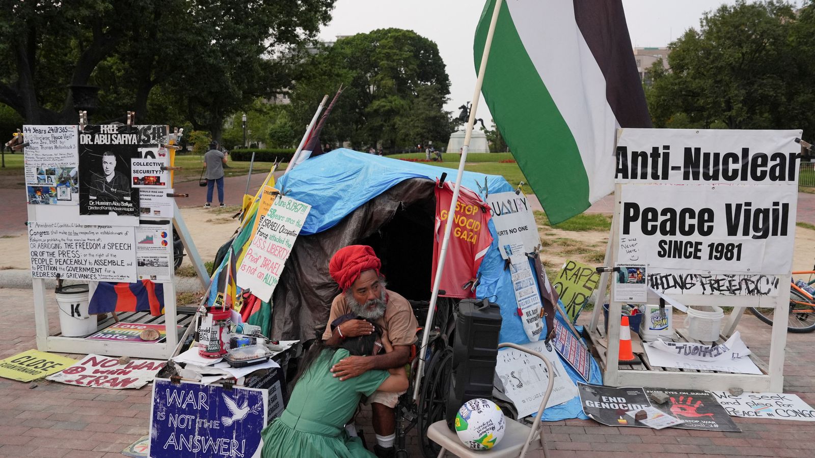 Vigil-keeper Philipos Melaku-Bello comforts a woman at the site after Donald Trump's order. Pic: Reuters