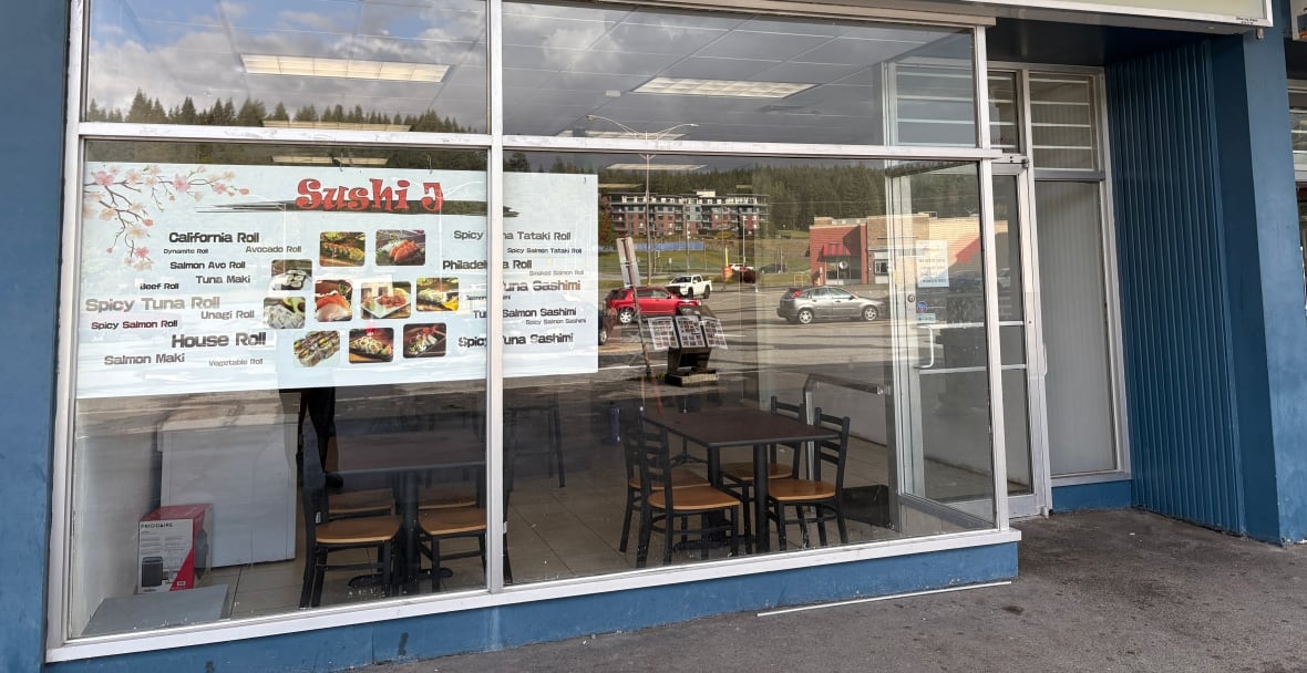 A storefront of a sushi restaurant, with a menu visible.