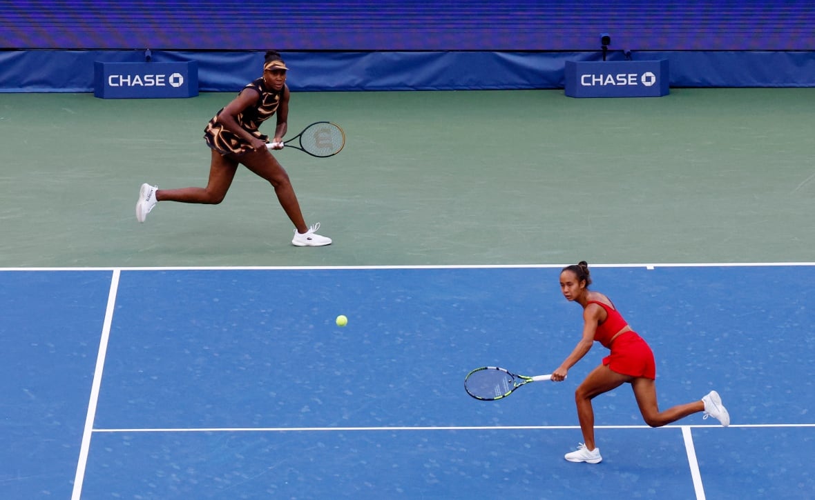 Two female athletes playing doubles tennis
