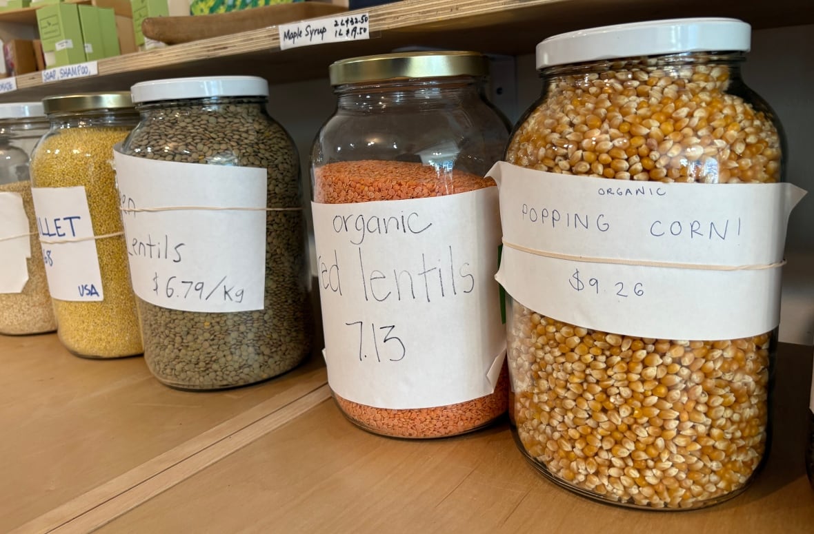 Large jars of popping corn, lentils and millet sit on a shelf.
