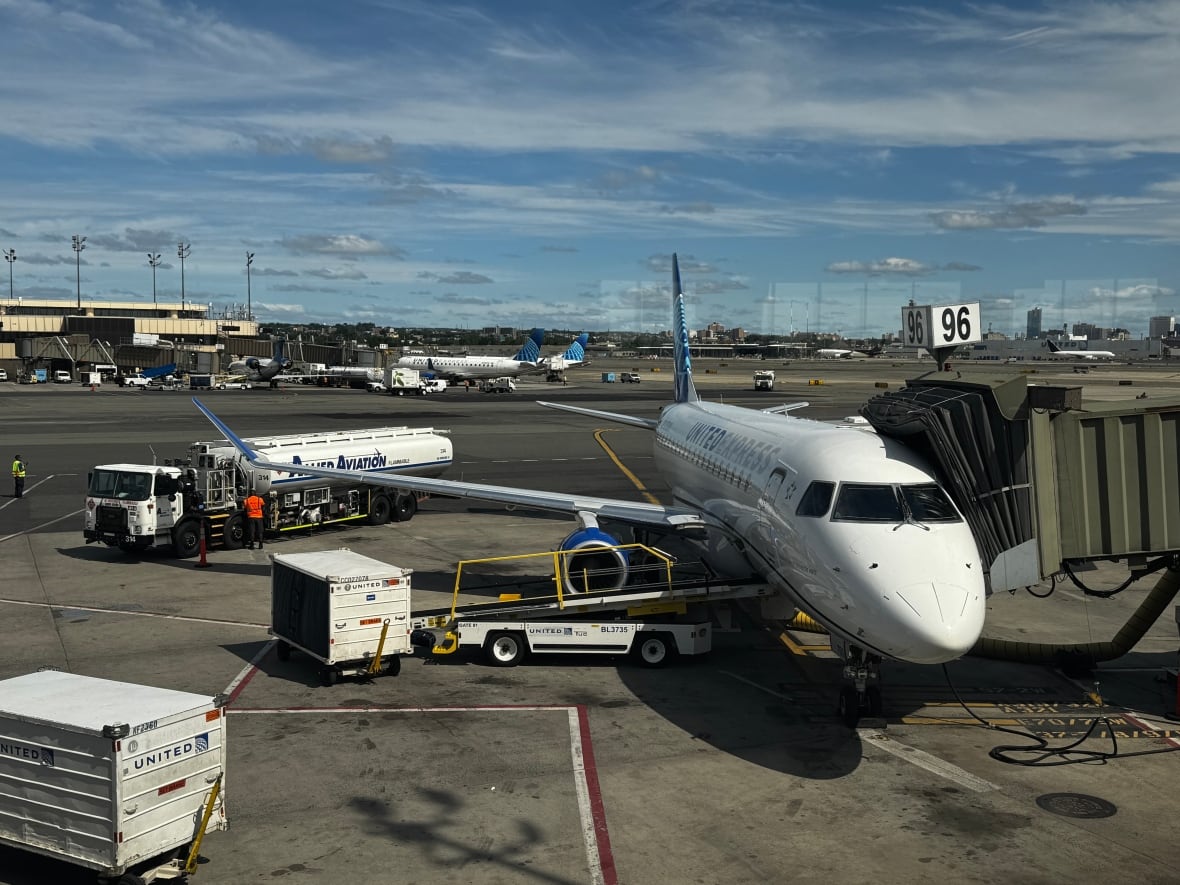 A white plane that says United on the side is parked on the tarmac in Newark, New Jersey. 