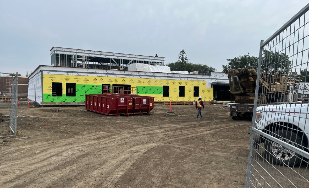 A building that's under construction with a large red dumpster sitting in front.